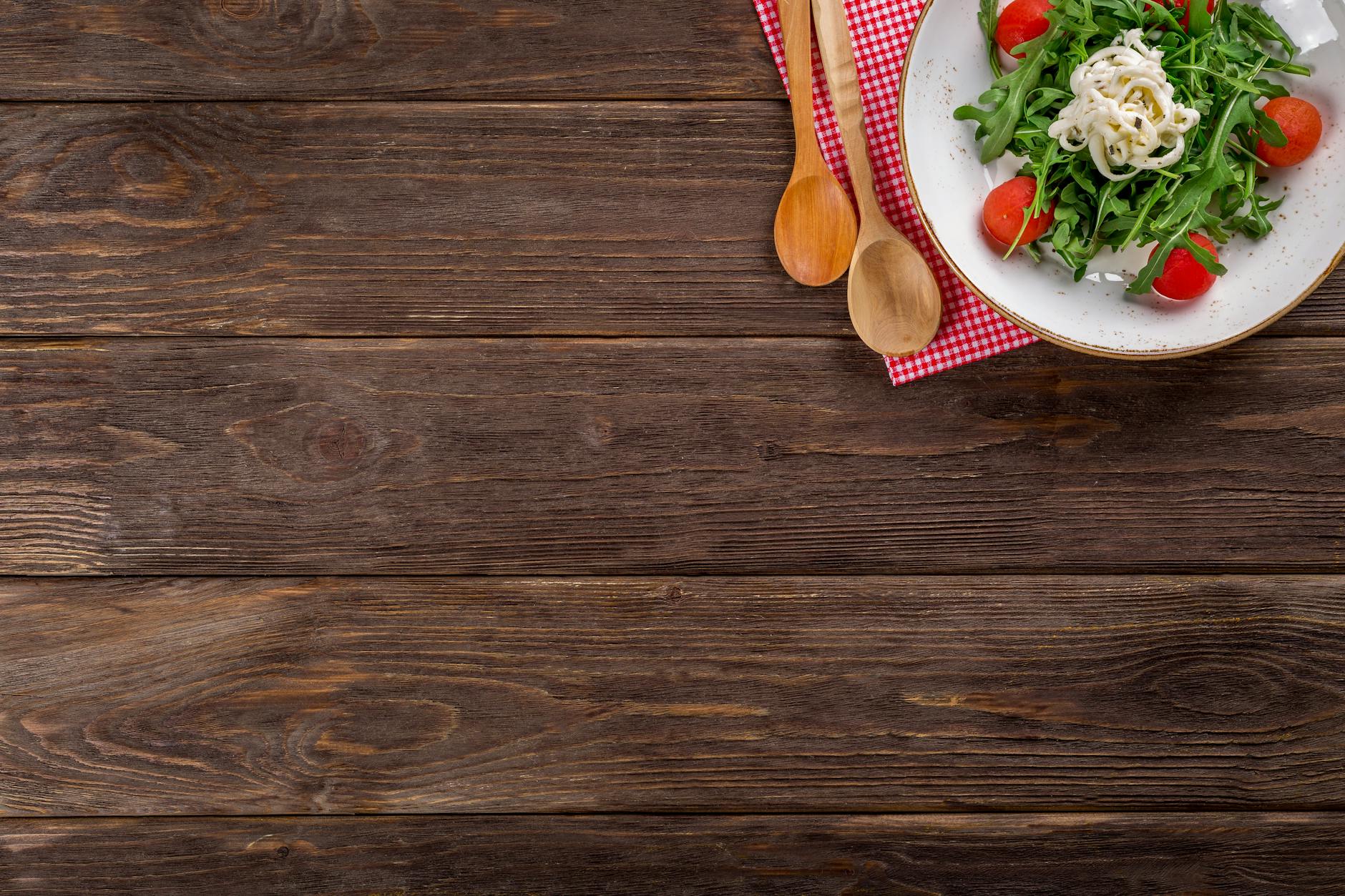 A delicious arugula salad with cherry tomatoes and pasta served on a rustic wooden table with space for text.