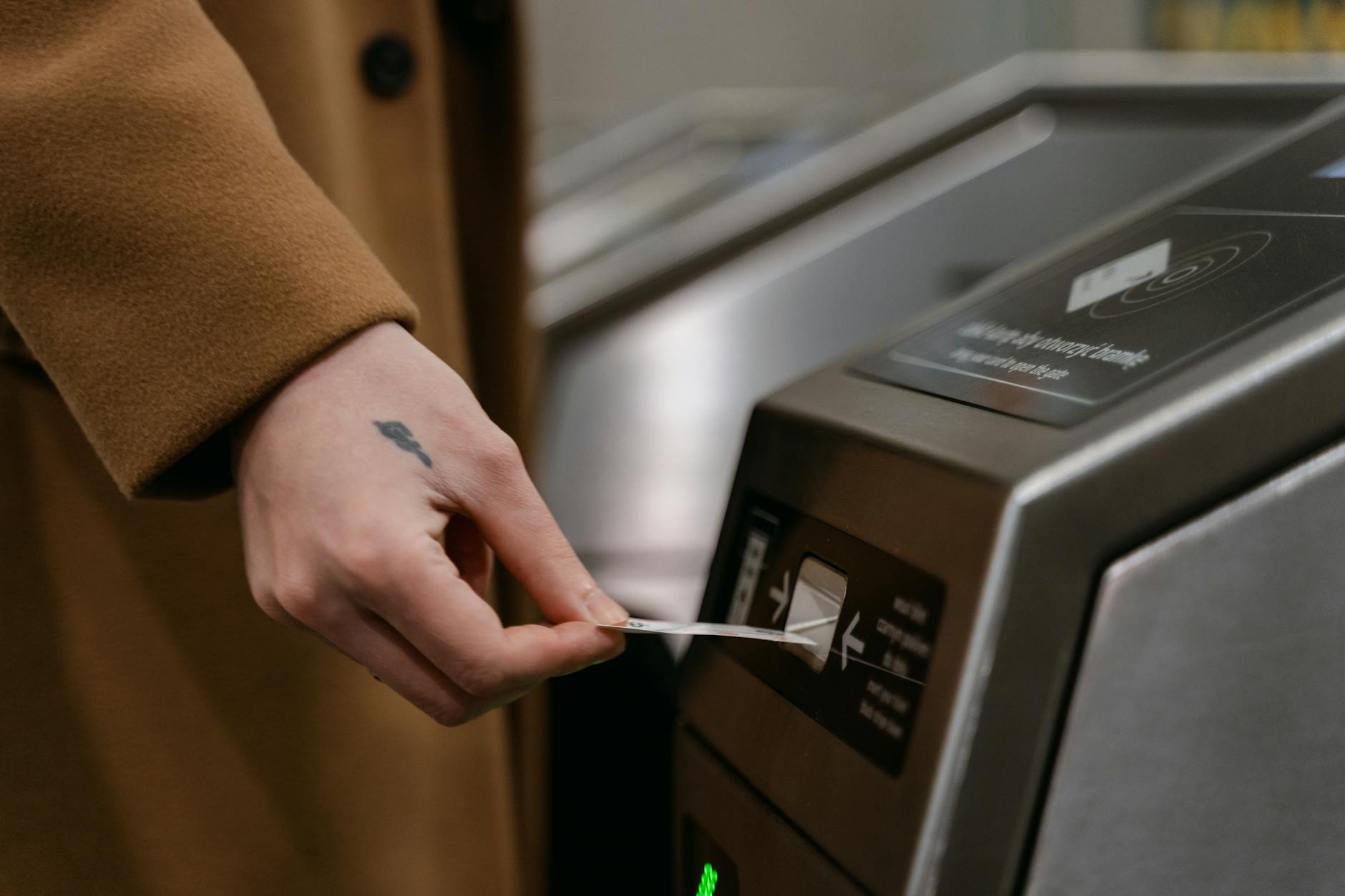 A person inserting a ticket into a turnstile at a train station, showcasing public transportation usage.